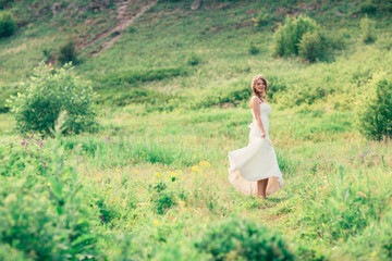 Naklejka na ściany i meble bride stands on a background of grass and mountains
