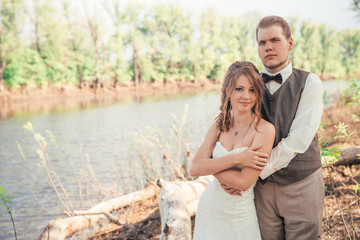 bride and groom standing arm in  against the background grass  lakes