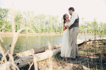 bride and groom standing arm in  against the background grass  lakes