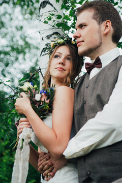 portrait of a bride and groom embrace on background leaves forest