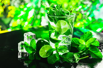 glass of mojito with lime and mint close-up ice cube on a dark background