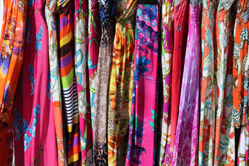 Rack of colorful dresses at an outdoor flea market