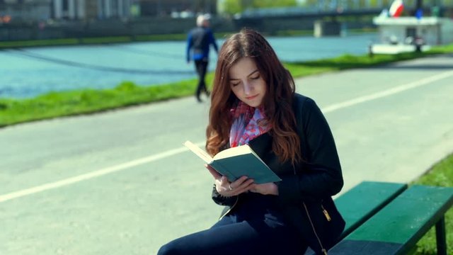 Girl finishes reading book and starts to relaxing on the bench
