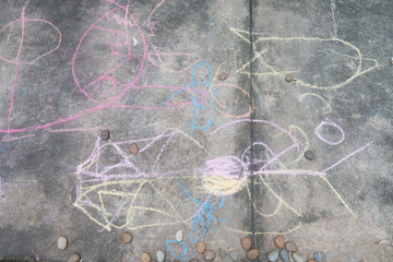 Little boy drawing and coloring by chalk on the ground