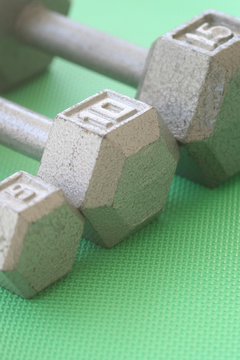 5, 10, and 15 lb hand weights in a row
Vertical orientation photograph of 5, 10, and 15 lb hand weights in a row on a green mat
