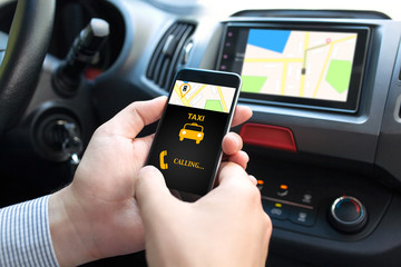man in car holding phone with app taxi and map