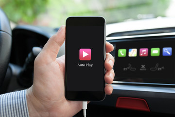 man hand in car holding phone with app Auto Play