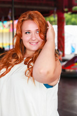 Fototapeta premium Portrait of a young, smiling plus size woman with long red hair.