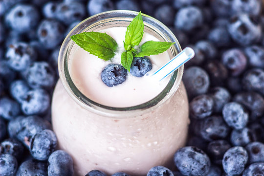 Beautiful appetizer blueberry fruit smoothie milk shake glass jar with juicy fresh berries background top view Yogurt cocktail Natural detox Liquid ice cream hurtleberry huckleberry winberry fraughan