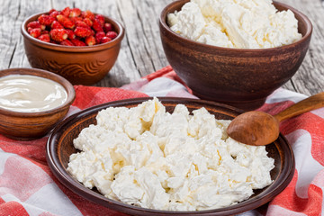 cottage cheese on clay plate, sour creamand strawberry in bowls