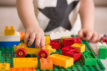 Close up of child's hands playing with colorful plastic bricks at the table. Toddler having fun and...