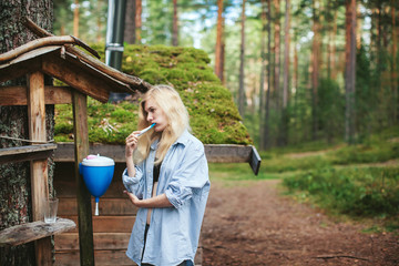 girl brushing teeth while in the woods near the house