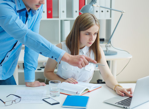 Young male IT consultant pointing at the screen while working with a colleague.