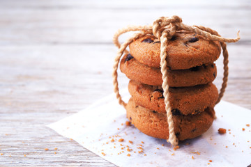Close up of a stack of chocolate chip cookies on a wooden table.