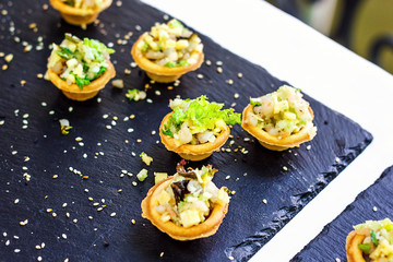Beautifully decorated catering banquet table with different food snacks and appetizers with sandwich, caviar, fresh fruits on corporate christmas birthday party event or wedding celebration