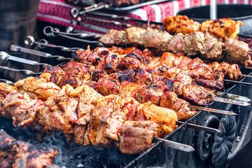 Grilling marinated shashlik preparing on a barbecue grill over charcoal. Shashlik is a form of...