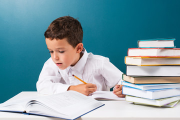 Pensive cute boy with homework sitting at a table