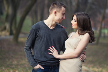 Young, happy and attractive couple enjoying together in walk through the city park. Urban outdoors.