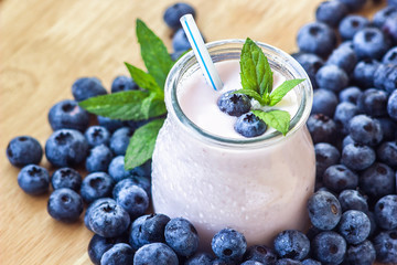 Beautiful appetizer blueberry fruit smoothie milk shake glass jar with juicy fresh berries background top view Yogurt cocktail Natural detox Liquid ice cream hurtleberry huckleberry winberry fraughan