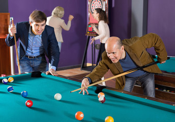 Group of charming positive friends playing billiards