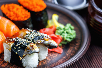 Sushi Set sashimi and sushi rolls served on dark plate. Image of Japanese food on dark background.