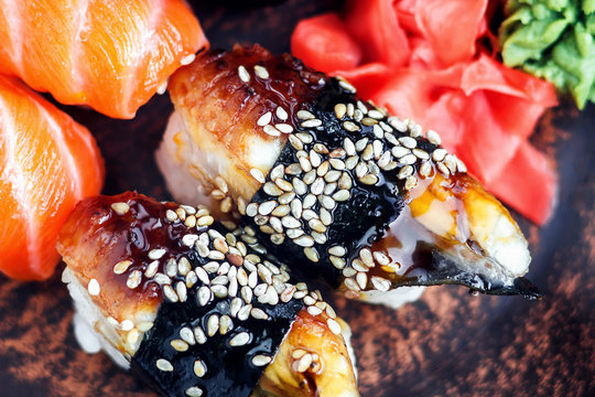 Sushi Set sashimi and sushi rolls served on dark plate. Image of Japanese food on dark background.