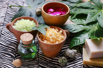 Bowls of green sea salt, bottle of essential oil and bars of soa