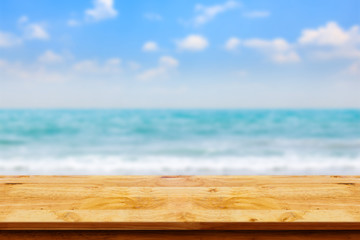 Empty top of wooden table on blurred beach background.