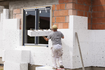 Workers spreading mortar over styrofoam insulation and mesh with trowel