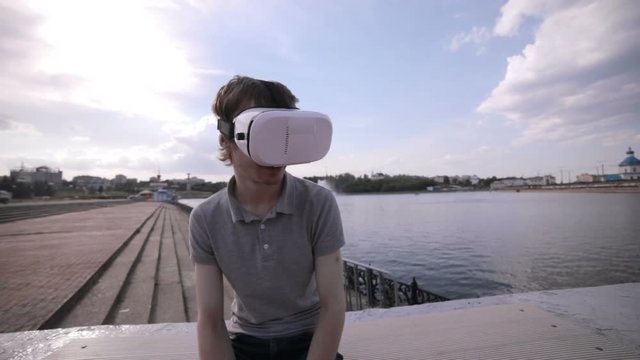Young handsome man wearing virtual reality goggles in a city. HD.