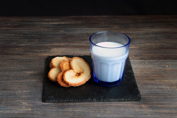Milk and cookies served on a black plate.