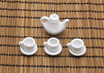 Toy cup and teapot on a napkin from a bamboo.