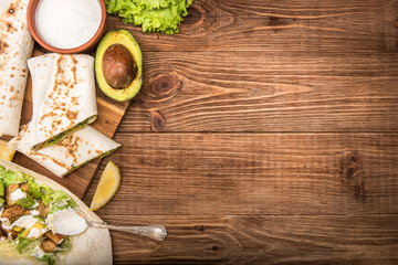 Fototapeta na wymiar Chicken, avocado and vegetables burrito on the wooden background.