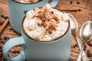 Cocoa with marshmallows and chocolate on a wooden table.