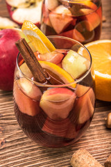 Homemade  red wine sangria with apples and oranges on a wooden table.