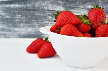 Ripe juicy strawberries in a white cup on a white table. Bright food
