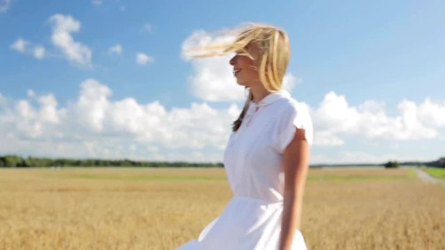 smiling young woman in white dress on cereal field