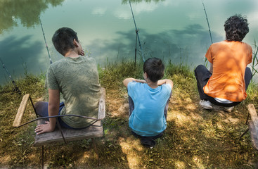 Father and sons fishing on river