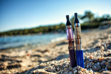 Two Electronic Cigarettes stuck in sand