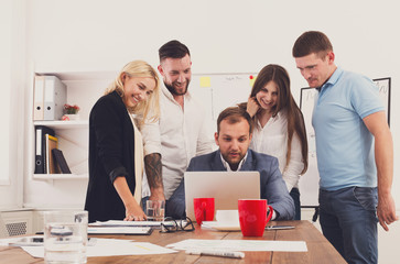 Happy business people team together look at laptop in office