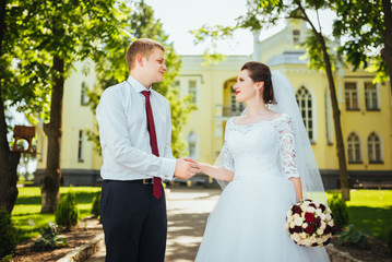 Bride and groom at wedding Day walking Outdoors on summer nature. Bridal couple, Happy Newlywed woman and man embracing. Loving wedding couple outdoor. Bride and groom