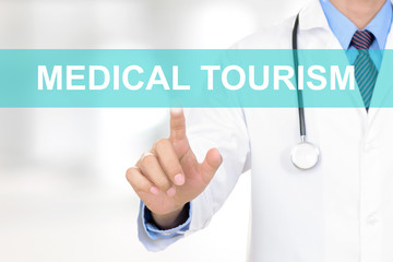 Doctor hand touching MEDICAL TOURISM sign on virtual screen