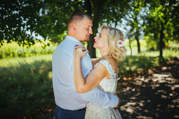 Obraz premium Bride and groom at wedding day, walking outdoor at summer on nature. Bridal couple, happy newlywed woman and man embracing. Loving wedding couple outdoor. 