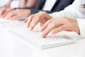 Hands typing on computer keyboards