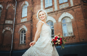 Fototapeta premium Beautiful smiling bride portrait near architecture with flowers