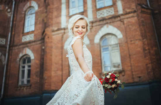 Beautiful smiling bride portrait near architecture with flowers