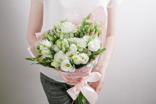 Florist at work. Make bouquet of white lisiantus . Vintage floristic background, colorful roses, antique scissors and a rope on an old wooden table