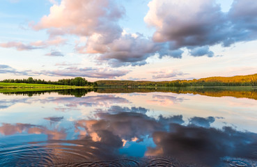 Calm lake at sunset clouds reflecting from surface
