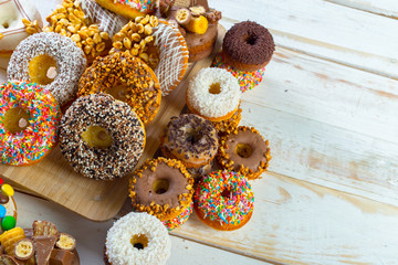 Collection of tasty donuts on white wooden board