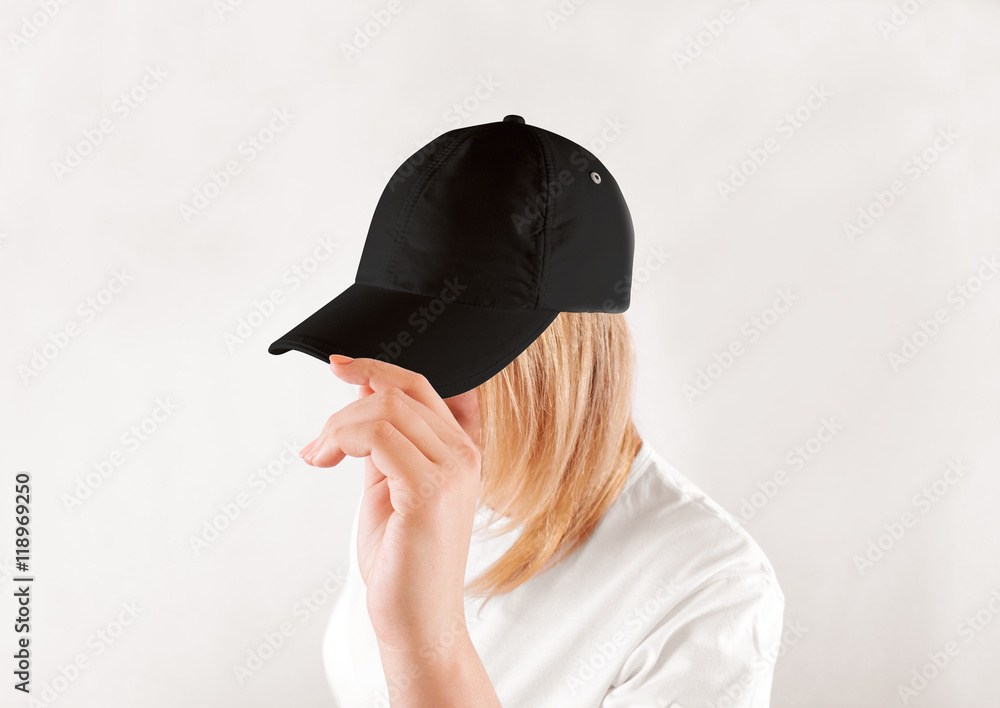 Wall mural Blank black baseball cap mockup template, wear on women head, isolated, side view. Woman in clear grey hat and t shirt uniform mock up holding visor of caps. Cotton basebal cap design on delivery guy.